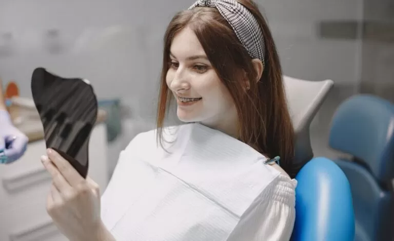 Girl smiling while looking at herself in mirror in dentist office